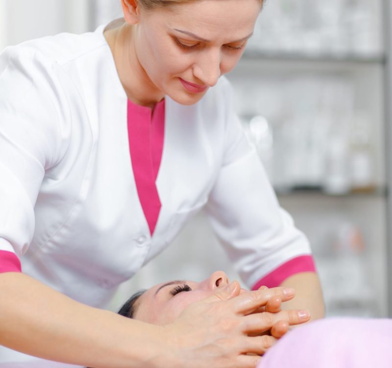 Doctor beautician doing facial massage in the spa salon. The procedure of facial massage in beauty salon. Face Skin Care. Cleansing Procedure. Cosmetology.
